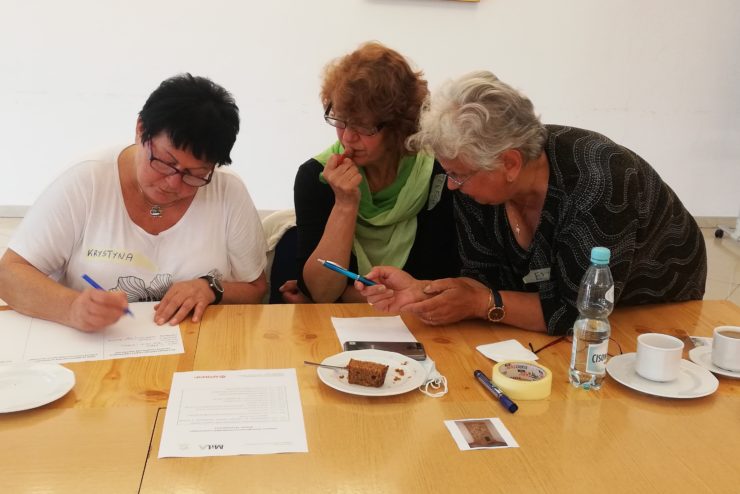 Trzy kobiety przy stole pochylające się nad kartkami papieru