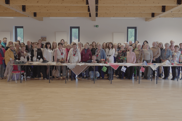 Zdjęcie dużej grupy seniorów w nowej sali z drewniana podłogą i sufitem