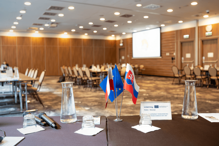 Pusta sala konferencyjna, na pierwszym planie flagi PL, SK, UE